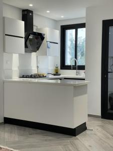 a white kitchen with a sink and a stove at Appartement de luxe lac 2 in La Goulette