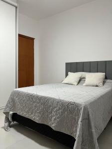 a white bedroom with a large bed with two pillows at Casa 331 in Jaguariúna