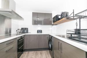 uma cozinha com armários de aço inoxidável e uma máquina de lavar louça em Modern, spacious entire 1 bedroom apartment. em Londres