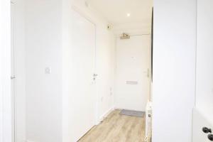 um corredor vazio com paredes brancas e um espelho em Modern, spacious entire 1 bedroom apartment. em Londres
