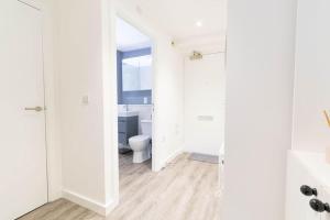 a white bathroom with a toilet and a mirror at Modern, spacious entire 1 bedroom apartment. in London