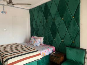 レッキにあるNew Travellers Lodge Sangotedo Lagosの緑の壁、ベッド付きのベッドルーム1室