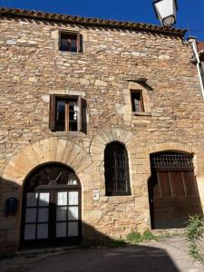un vieux bâtiment en pierre avec deux portes et fenêtres dans l'établissement 13th Century Stone House, à Faugères