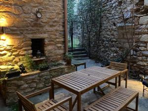 a patio with a wooden table and chairs and a stone wall at 13th Century Stone House in Faugères