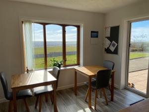 a dining room with a table and chairs and windows at Aultnagar Accommodation in Orkney