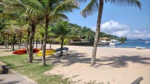 a beach with palm trees and a boat on it at Portogalo, suíte com SPA in Angra dos Reis