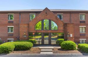 ein Backsteingebäude mit einer gewölbten Tür mit Büschen in der Unterkunft Extended Stay America Suites - Raleigh - Cary - Harrison Ave in Cary