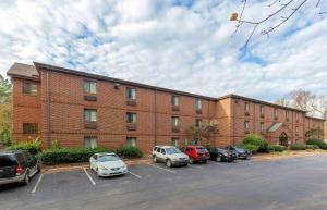 a brick building with cars parked in a parking lot at Extended Stay America Suites - Raleigh - North Raleigh - Wake Towne Dr in Raleigh