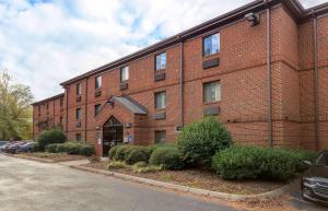 a brick building with cars parked in front of it at Extended Stay America Suites - Raleigh - North Raleigh - Wake Towne Dr in Raleigh