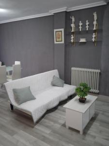 a living room with a white couch and a table at Apartamento Roma in Ciudad-Rodrigo