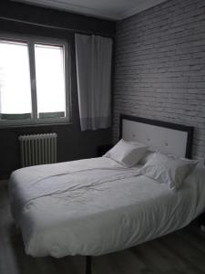 a bed in a bedroom with a brick wall at Apartamento Roma in Ciudad-Rodrigo