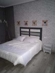 a bedroom with a white bed and a brick wall at Apartamento Roma in Ciudad-Rodrigo
