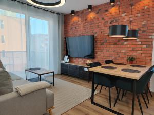 a living room with a table and a brick wall at STARCO Apartamenty Centrum in Stargard