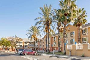 a parking lot in front of a building with palm trees at Extended Stay America Suites - Los Angeles - Ontario Airport in Guasti