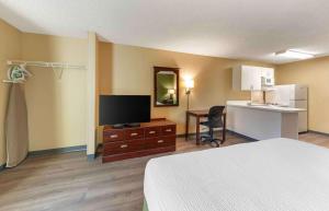 a room with a bed and a television and a kitchen at Extended Stay America Suites - Los Angeles - Ontario Airport in Guasti