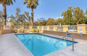 a swimming pool with tables and chairs and palm trees at Extended Stay America Suites - Los Angeles - Ontario Airport in Guasti