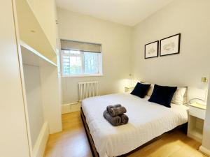 Kennington retreat with garden + king bed في لندن: غرفة نوم مع سرير مع دمية دب عليها