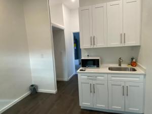 uma cozinha branca com um lavatório e um micro-ondas em Entire private Studio apartment em North Miami Beach