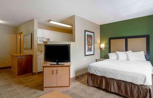 Extended Stay America Select Suites Tampa Airport Memorial Hwy في تامبا: غرفة فندقية بسرير وتلفزيون بشاشة مسطحة