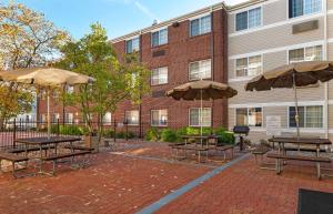 a patio with tables and umbrellas in front of a building at Extended Stay America Suites - Cincinnati - Blue Ash - Reed Hartman in Blue Ash