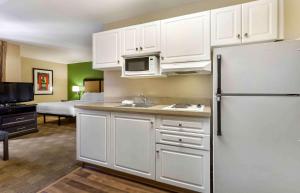 a kitchen with white cabinets and a refrigerator in a room at Extended Stay America Suites - Phoenix - Biltmore in Phoenix