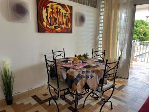 uma mesa de jantar com cadeiras e um quadro na parede em La Maison Vintage em Petit-Bourg