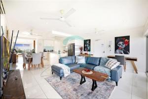 Una sala de estar con un sofá azul y una mesa. en ZEN TOWERS: Cozy Executive 3-BR Family Apt in Darwin City, en Darwin