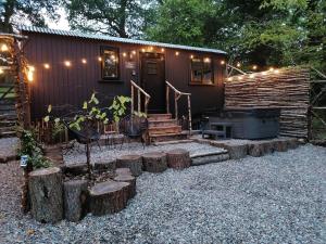 a small cabin with a grill and some logs at The Mar Huts - The Conic Hut in Drymen