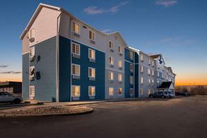 un gran edificio con coches estacionados en un estacionamiento en WoodSpring Suites Champaign near University, en Champaign