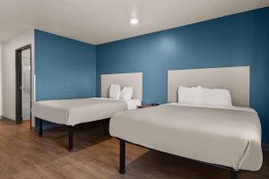 2 camas en una habitación con una pared azul en WoodSpring Suites Champaign near University, en Champaign