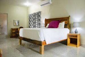 a bedroom with a large bed with white sheets and purple pillows at DEMAROYS in Treasure Beach