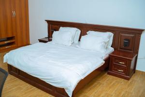 uma cama com uma cabeceira em madeira e lençóis e almofadas brancos em 1 Bedroom Bungalow in Alalubosa GRA em Ibadan