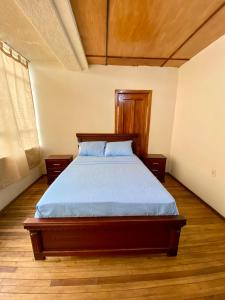 a bedroom with a bed with a wooden headboard at Airbnb_espinoza in Cuenca