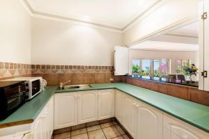 una cucina con armadi bianchi e piano di lavoro verde di Tranquil Garden Hideaway a Ormeau