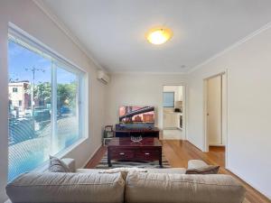 sala de estar con sofá y ventana grande en Ground floor one bedroom apartment in Elsternwick, en Melbourne