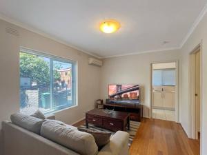 sala de estar con sofá y TV de pantalla plana en Ground floor one bedroom apartment in Elsternwick, en Melbourne