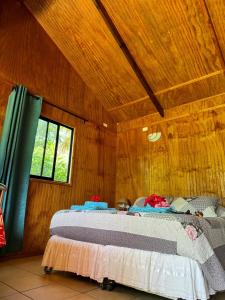 a bedroom with a bed in a wooden wall at Cabañas Tangaroa y Hamea in Hanga Roa