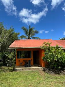 una pequeña casa con techo naranja y palmera en Cabañas Tangaroa y Hamea en Hanga Roa