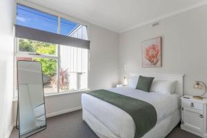 a white bedroom with a bed and a window at Sea You Soon: Views Parking & WiFi in Burnie
