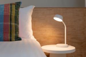 una lámpara blanca en una mesa junto a una cama en City Lights & Tiny Delights: Near CBD =& Parking, en Kings Park