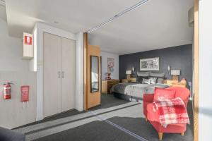 um quarto com uma cama e uma cadeira vermelha em The Treehouse Retreat em Grindelwald