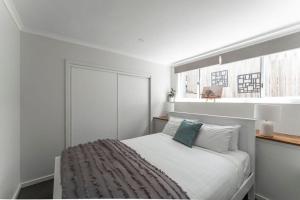 a white bedroom with a bed with a window at Cosy Unit With a Sea View in Burnie