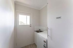 a white kitchen with a door and a window at Cosy Unit With a Sea View in Burnie