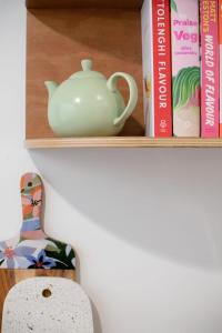 a shelf with a tea pot and books at Little City Cottage with Free Onsite Parking in Launceston