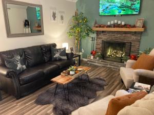 a living room with a leather couch and a fireplace at Cute private Wooded Cabin near the big lake in Tafton