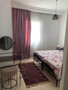 een slaapkamer met een bed, een tafel en een spiegel bij Charmant appartement à la Soukra in La Soukra