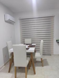 une salle à manger avec une table et des chaises blanches dans l'établissement Hermosos apartamentos en caribe campestre, coveñas, à Coveñas
