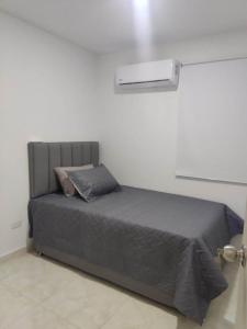Ce lit se trouve dans une chambre blanche dotée d'une couverture grise. dans l'établissement Hermosos apartamentos en caribe campestre, coveñas, à Coveñas