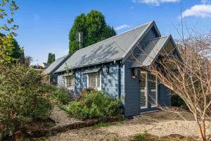 a blue house with a solar roof at Duck Walk Cottage - Boutique Studio Retreat in Burradoo