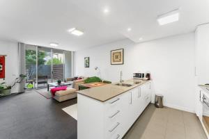 Una cocina con gabinetes blancos y una sala de estar. en Tranquil 1-Bed Apartment with Courtyard, Pool, BBQ, en Phillip 4 fotos más